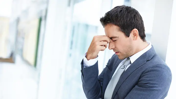 Mann hält sich angestrengt die Hand vor sein Gesicht.