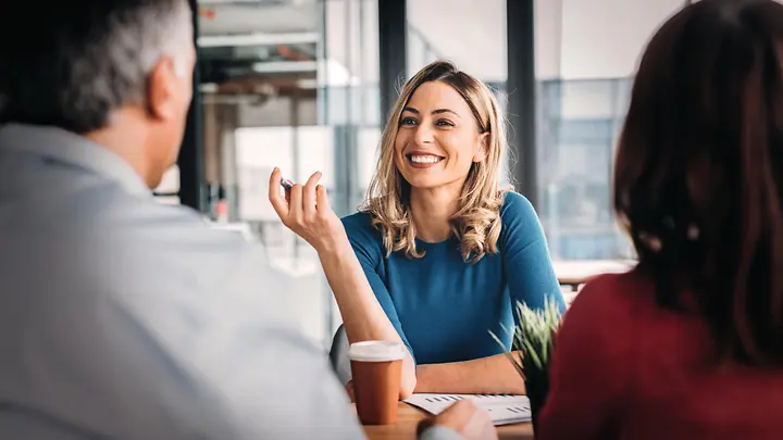 Eine Frau, die in einem Gespräch mit zwei Personen ist.