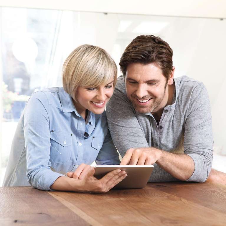 Ein Mann und eine Frau schauen zusammen auf ein Tablet.