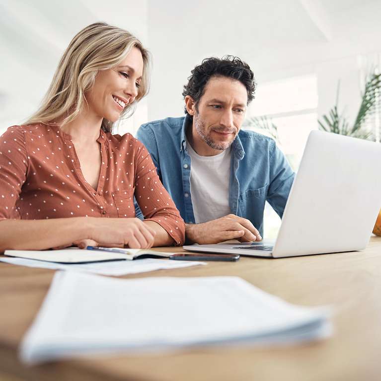 Eine Frau und ein Mann schauen zusammen auf einen Laptop.