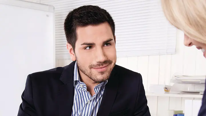 Ein Mann zeigt mit seinem Finger auf ein Dokument, das auf dem Tisch liegt.