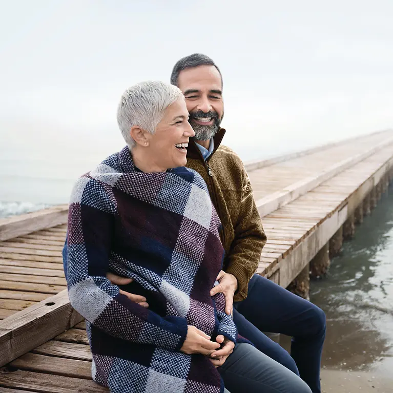 Ein Mann und eine Frau sitzen auf einem Steg, der ins Wasser führt.