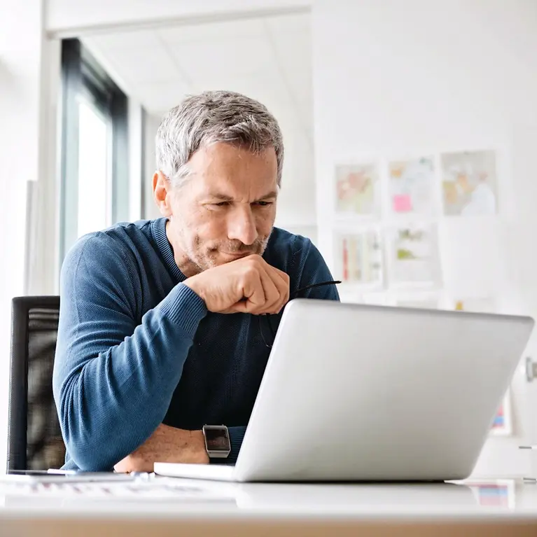 Der Mann schaut nachdenklich auf seinen Laptop.