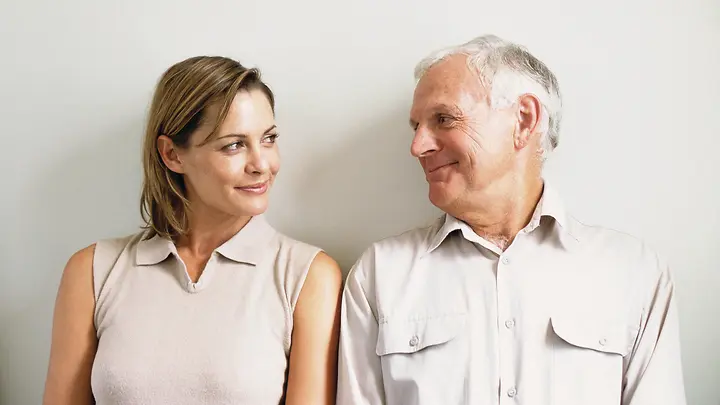 Eine junge Frau und ein älterer Mann lächeln sich an.