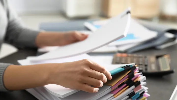 Jemand sortiert Dokumente auf dem Schreibtisch.