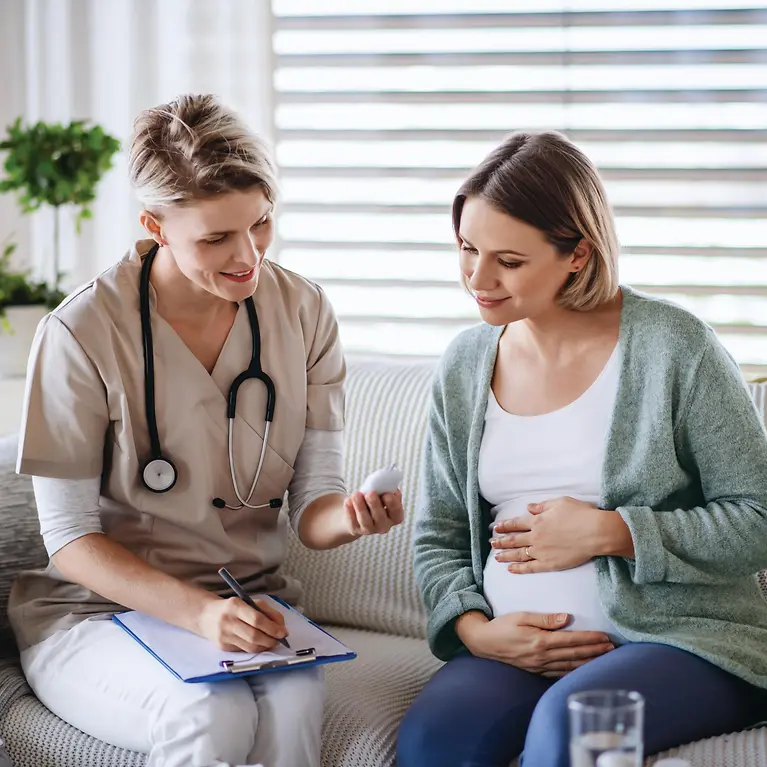 Man sieht eine Krankenschwester und eine Schwangere Frau.