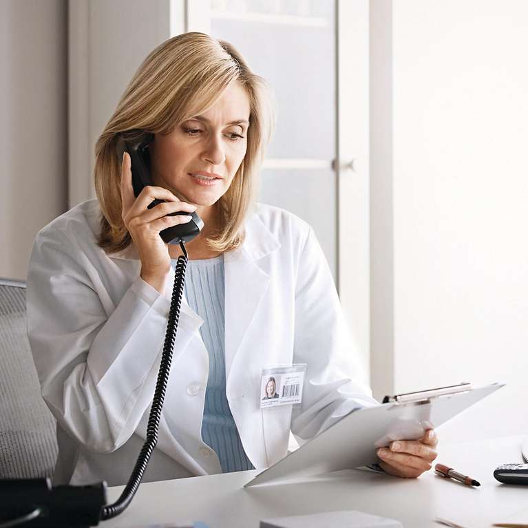 Eine Ärztin hat ein Telefon in der Hand und telefoniert.