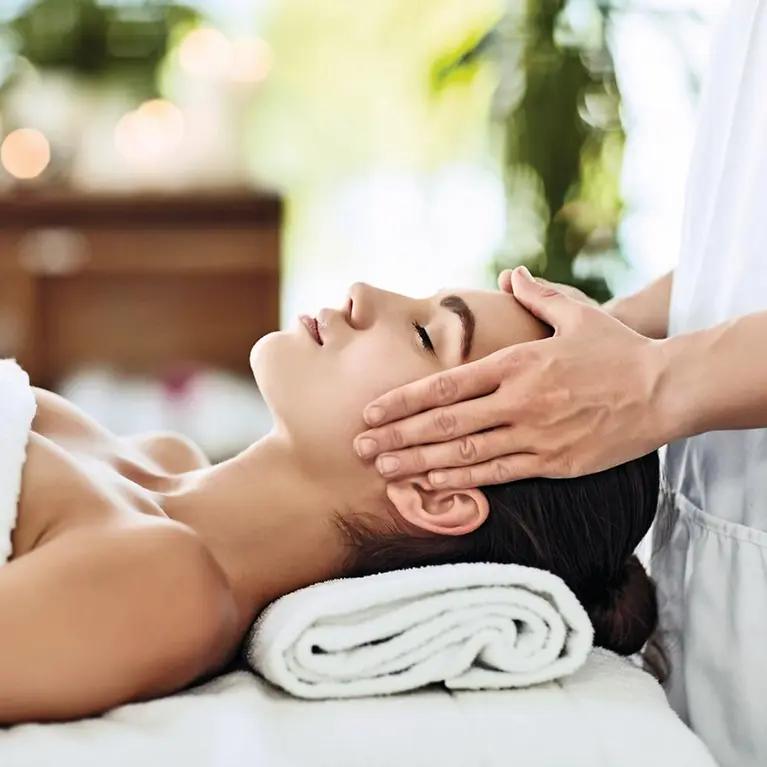 Eine Frau liegt auf einer Massageliege und ihr Gesicht wird massiert.
