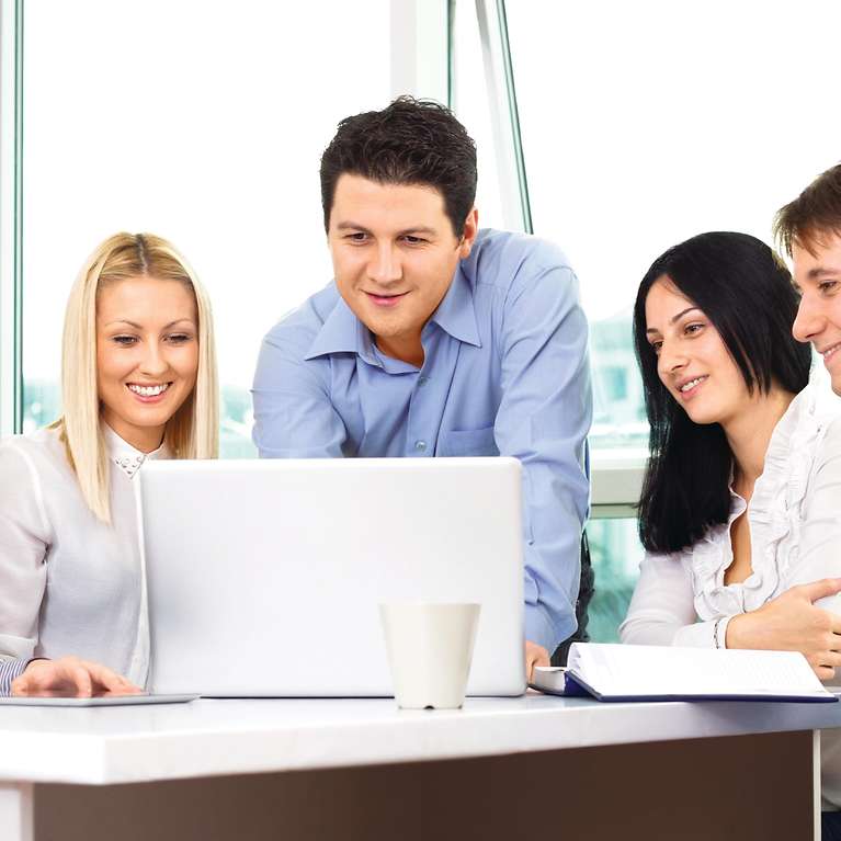 Mehrere Menschen schauen alle zusammen auf einen Laptop.