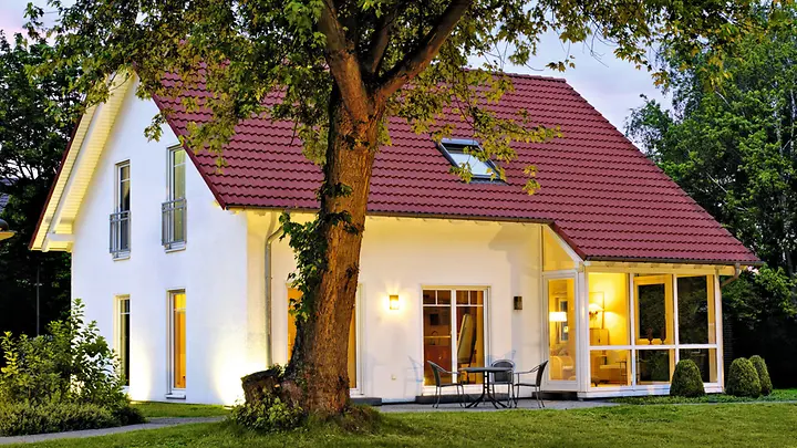 Man sieht ein Haus, das mit Außenbeleuchtung beleuchtet ist.